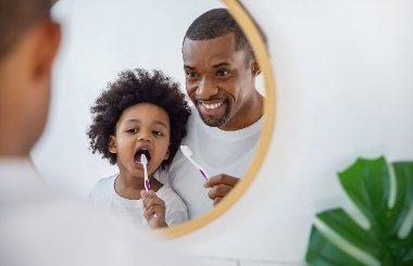 Photo of father and child brushing teeth in the bathroom