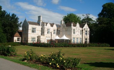 External view of Barra Hall main building with blue sky behind and flower beds in foreground