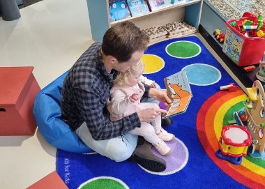 An adult man and little girl read a book at the bunker