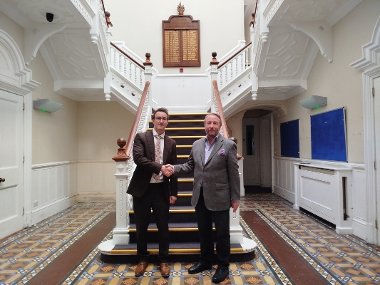 Cllr Jonathan Bianco and Keith Smith, CEO of HRUC, shake hands at the foot of the staircase of Barra Hall to mark the completed sale.