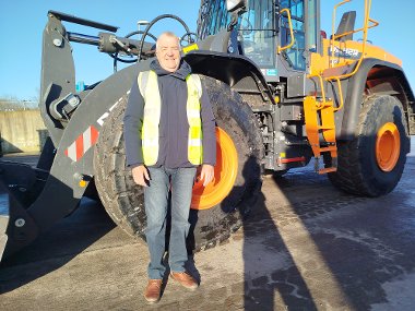 Cllr Eddie Lavery stands in front of a new Develon shove at the Harefield Civic Amenity Site.